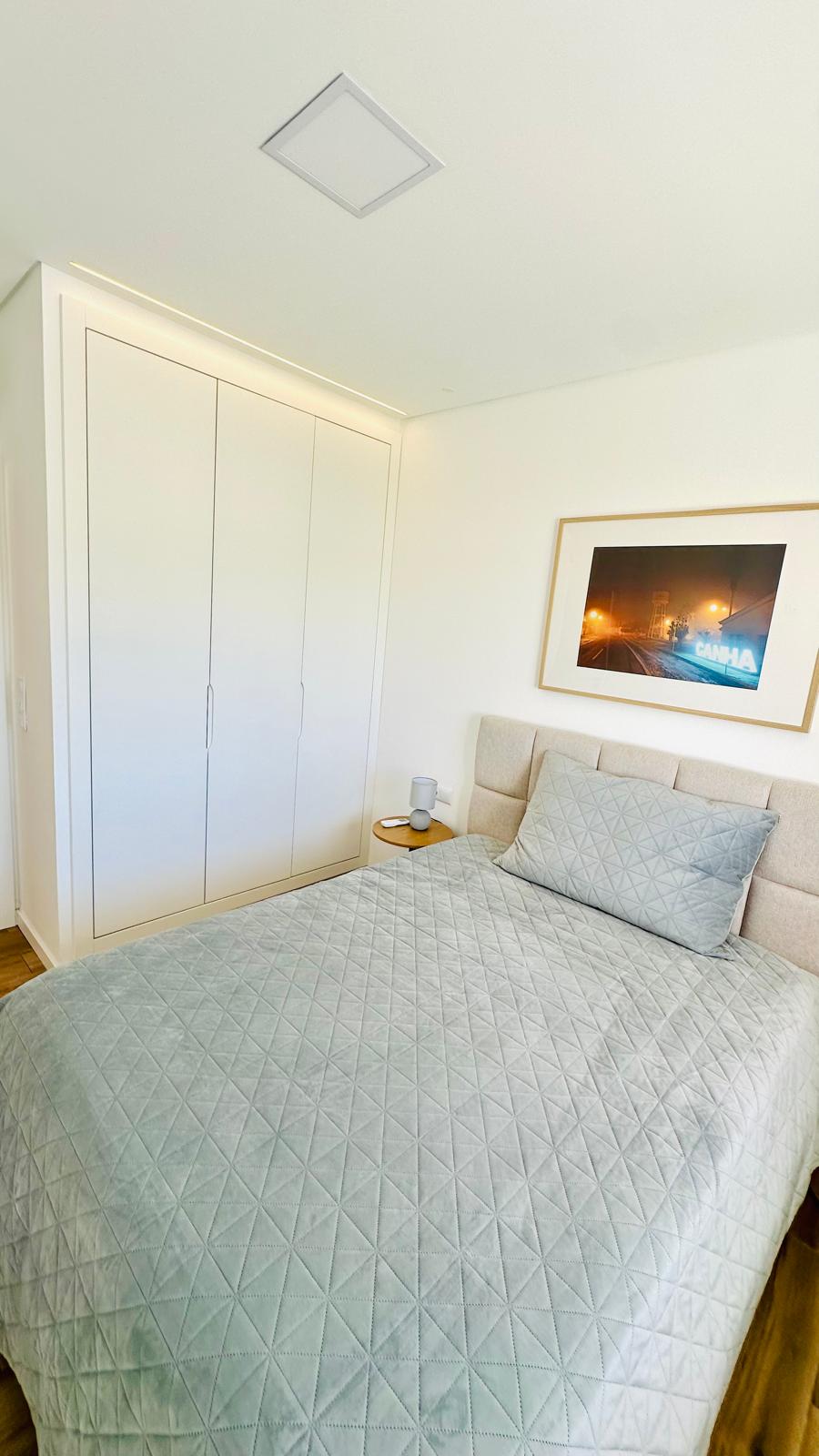 Quarto com cama, roupeiro embutido e mesa de cabeceira