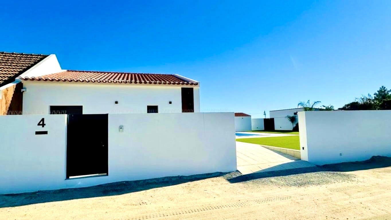 Entrada da moradia com portão e muros brancos