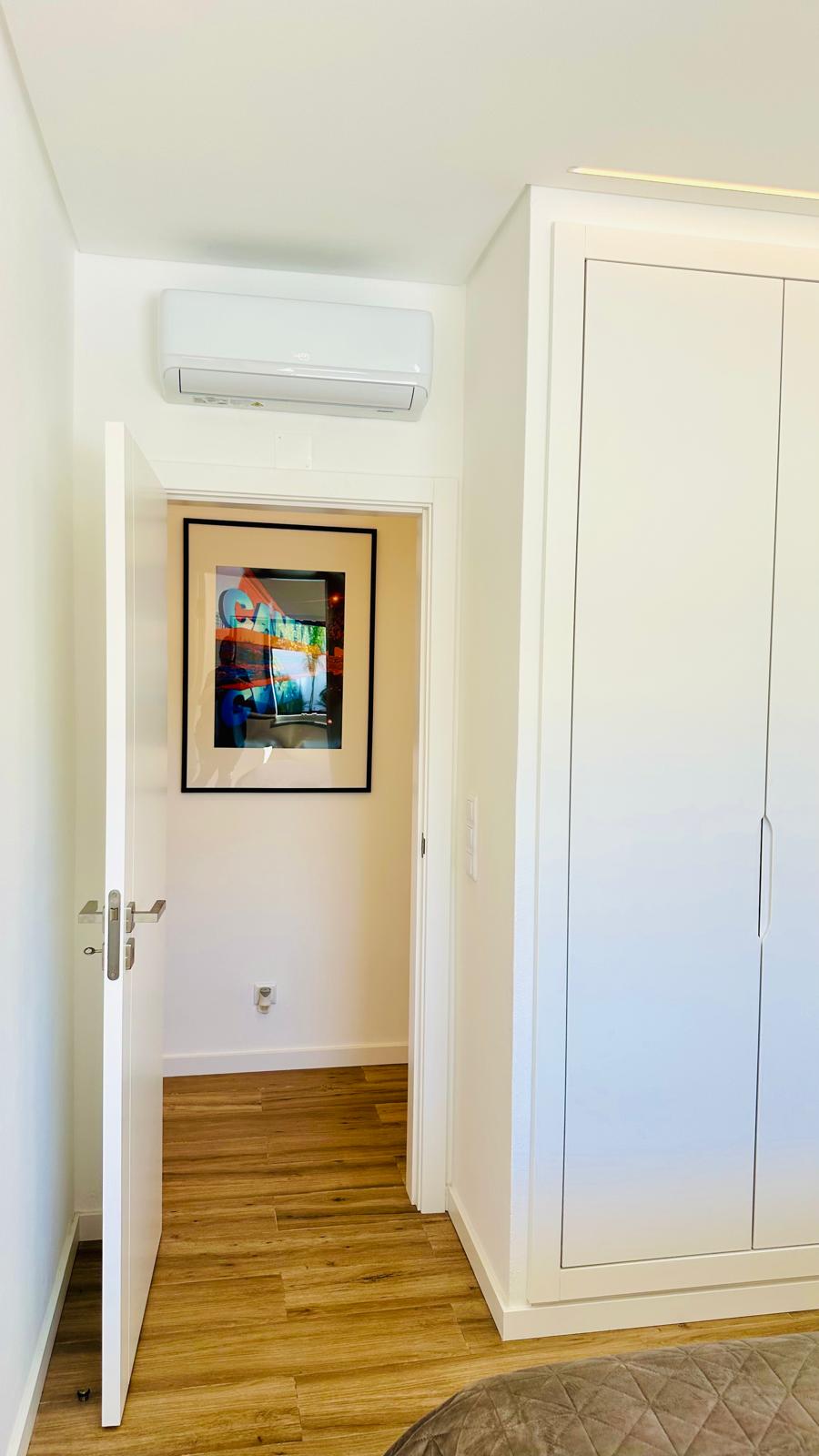 Quarto com roupeiros brancos e passagem para o corredor